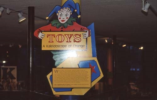 Title of exhibit on wall with cut-out of jack-in-the-box toy behind it